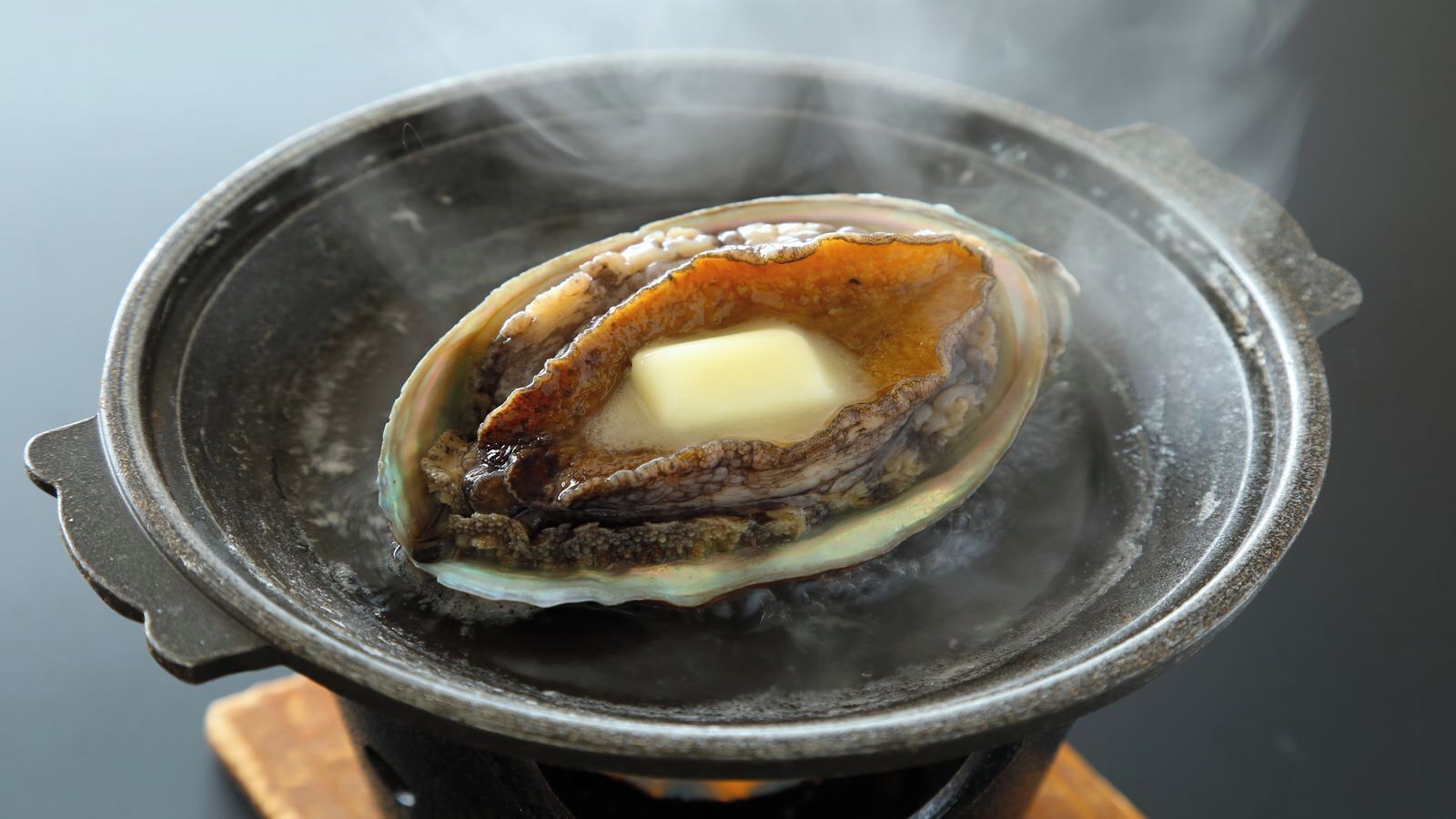 A single oyster with a pat of butter on a hot plate.