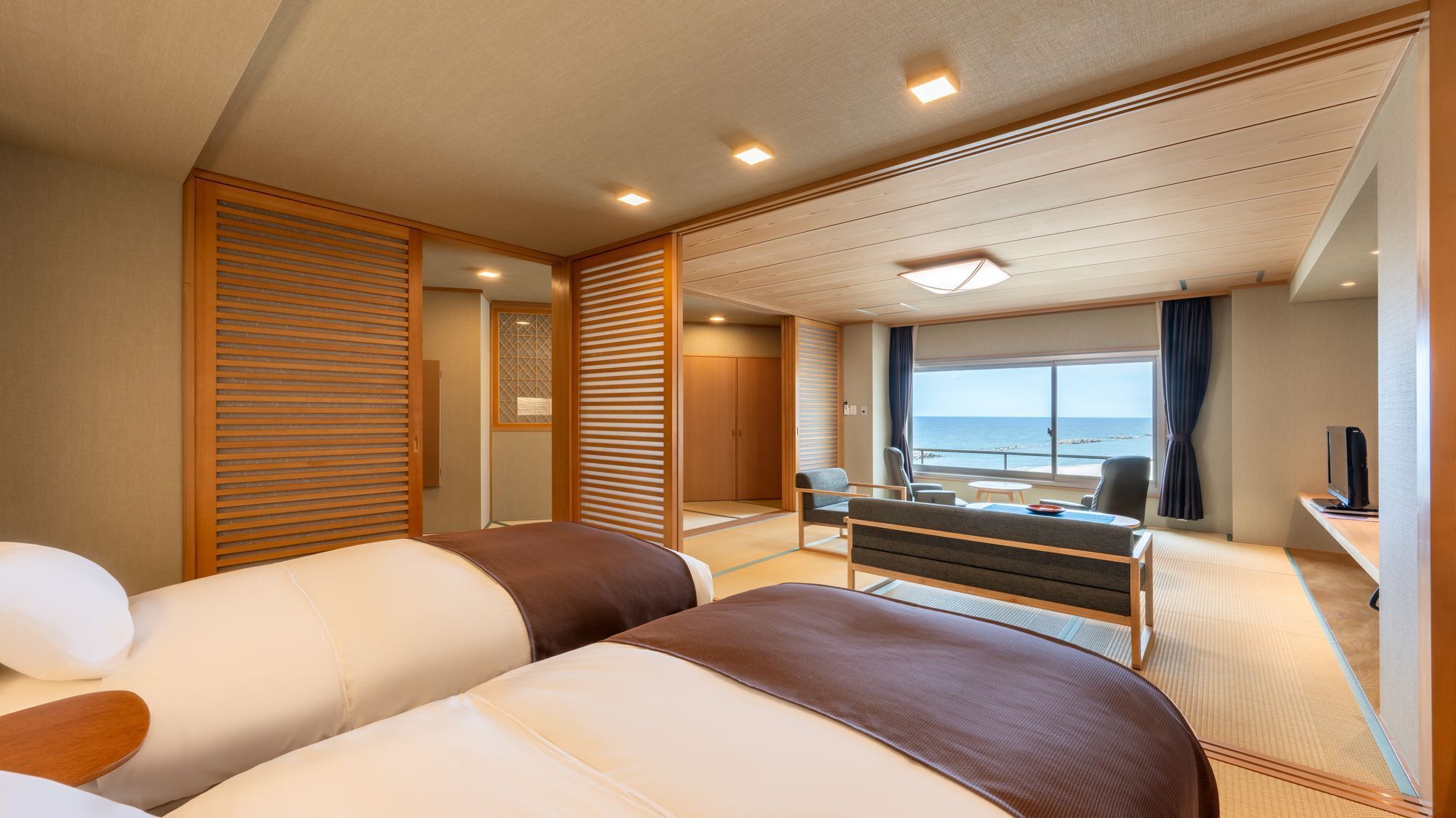 Habitación de hotel con cama, escritorio, silla y vista al mar.