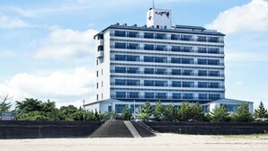Un hotel de varios pisos con una escalera que lleva a la entrada, ubicado en la playa y con vista al mar.