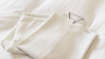 A neatly folded white garment on a bed with a smooth texture.