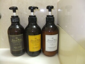 Three bottles of Orange Rose body care products on a bathroom counter. - Bright Park Hotel (Kochi)