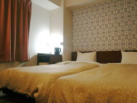 Habitación de hotel con dos camas, una mesita de noche, una cafetera y un cabecero estampado.