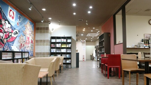 A library with bookshelves, reading chairs, and a mural on the wall. - Hamamatsu Station Hotel (Hamamatsu)