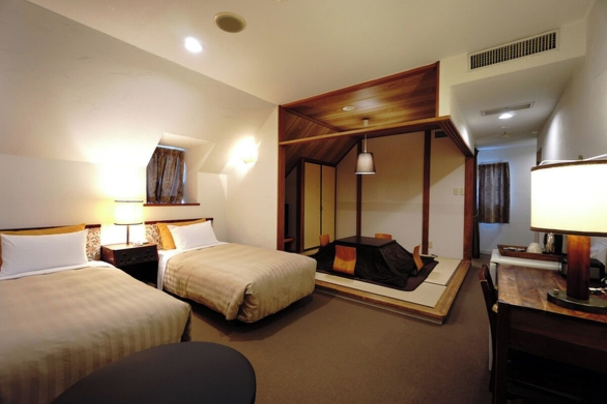 Habitación de hotel con dos camas, un escritorio y zona de estar.