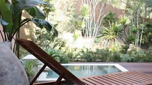 A wooden deck with a lounge chair and a stone planter. - Time Resort Kakureya (Ibaraki)