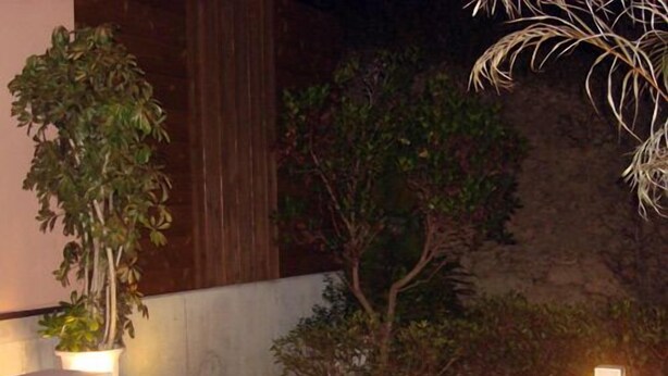 A hot tub with a wooden deck, surrounded by plants and a stone wall. - Time Resort Kakureya (Ibaraki)