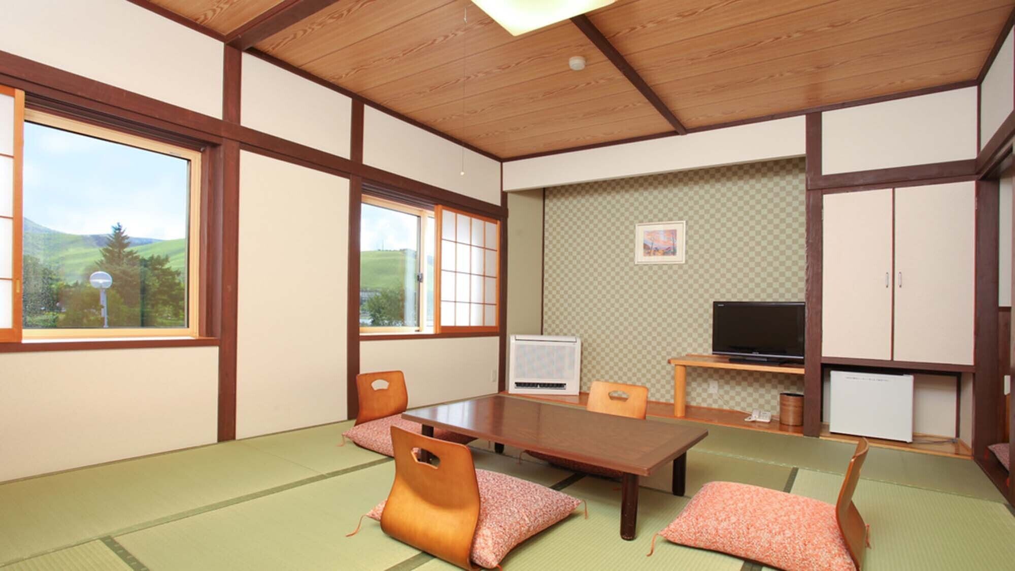 Una habitación japonesa tradicional con suelo de tatami, una mesa baja, sillas, un televisor y un armario.