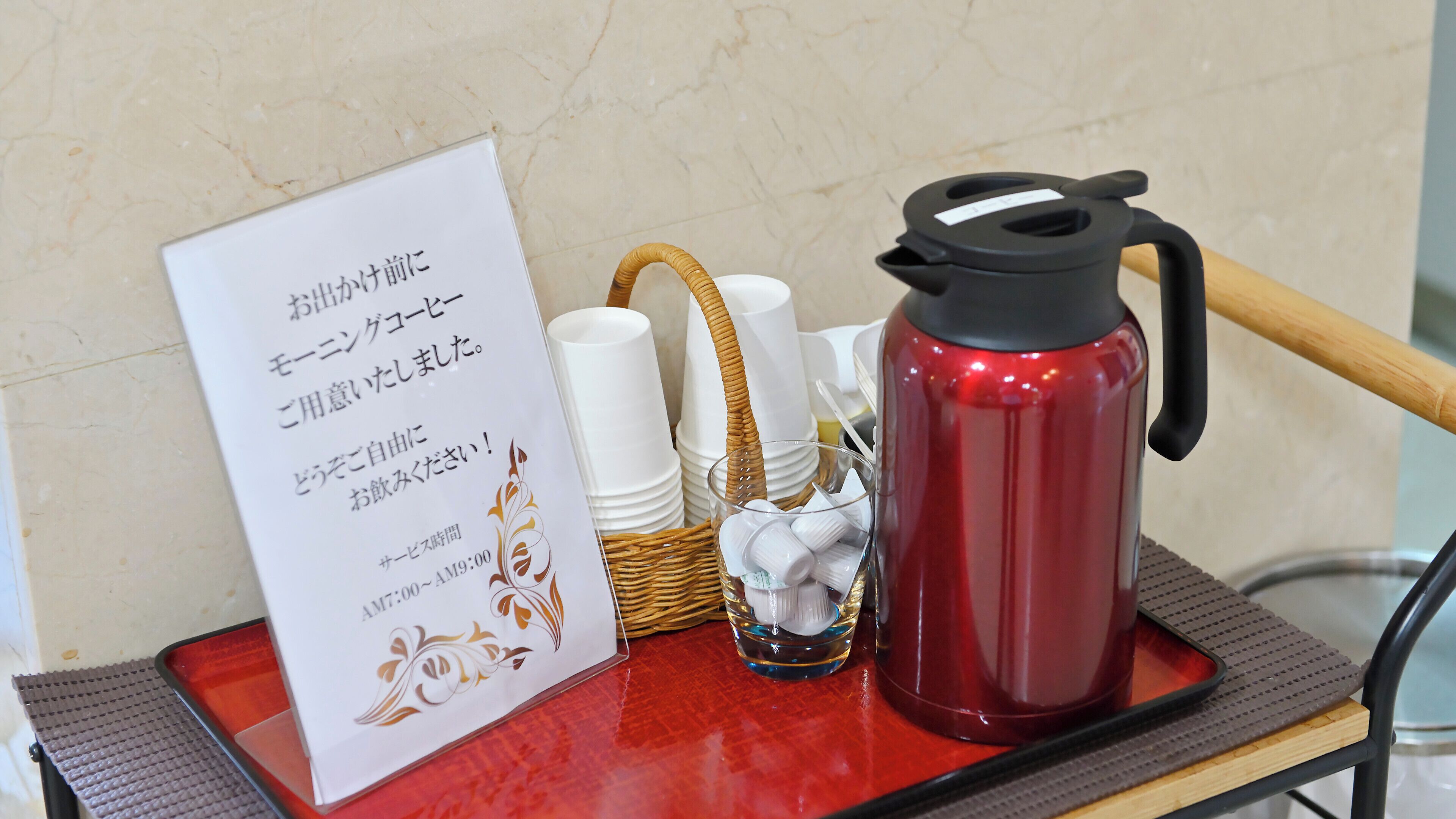 A table with a red water bottle, a glass, and a sign with Japanese text.