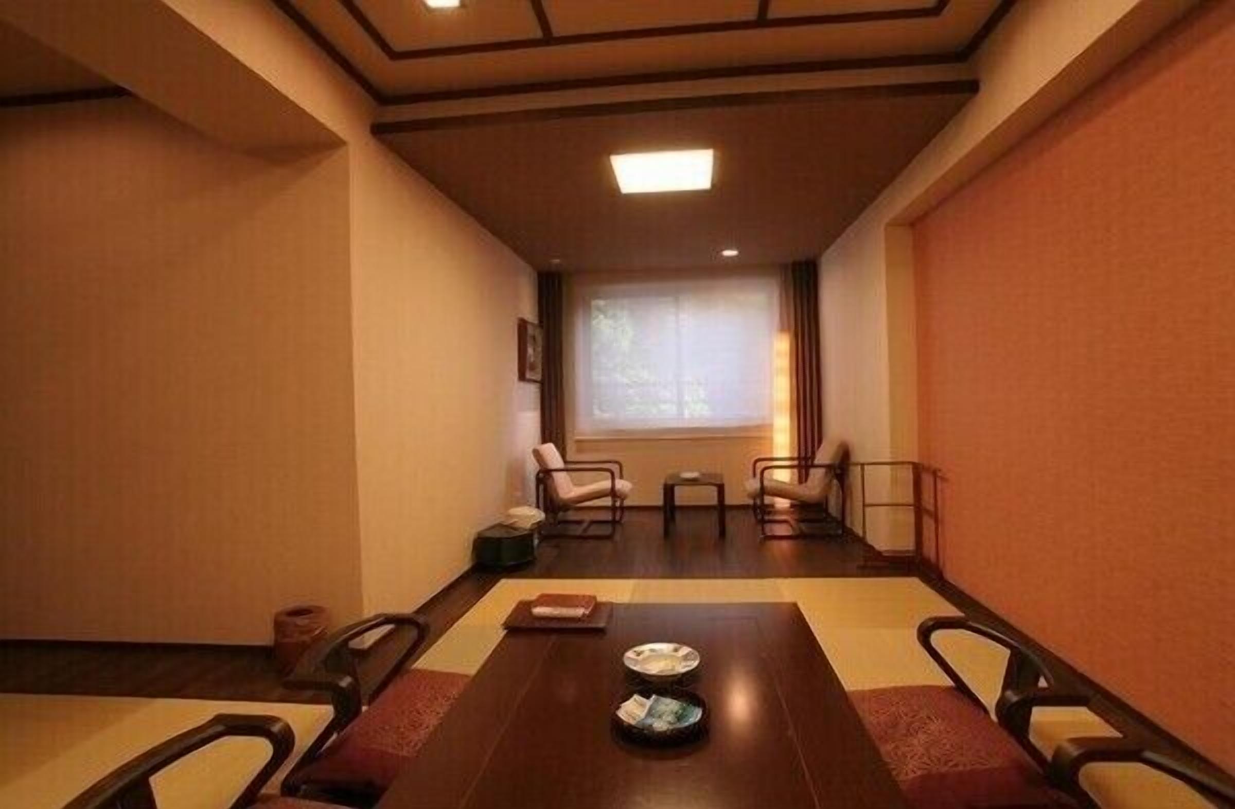A meeting room with a long table, chairs, a window, and a view of trees outside.
