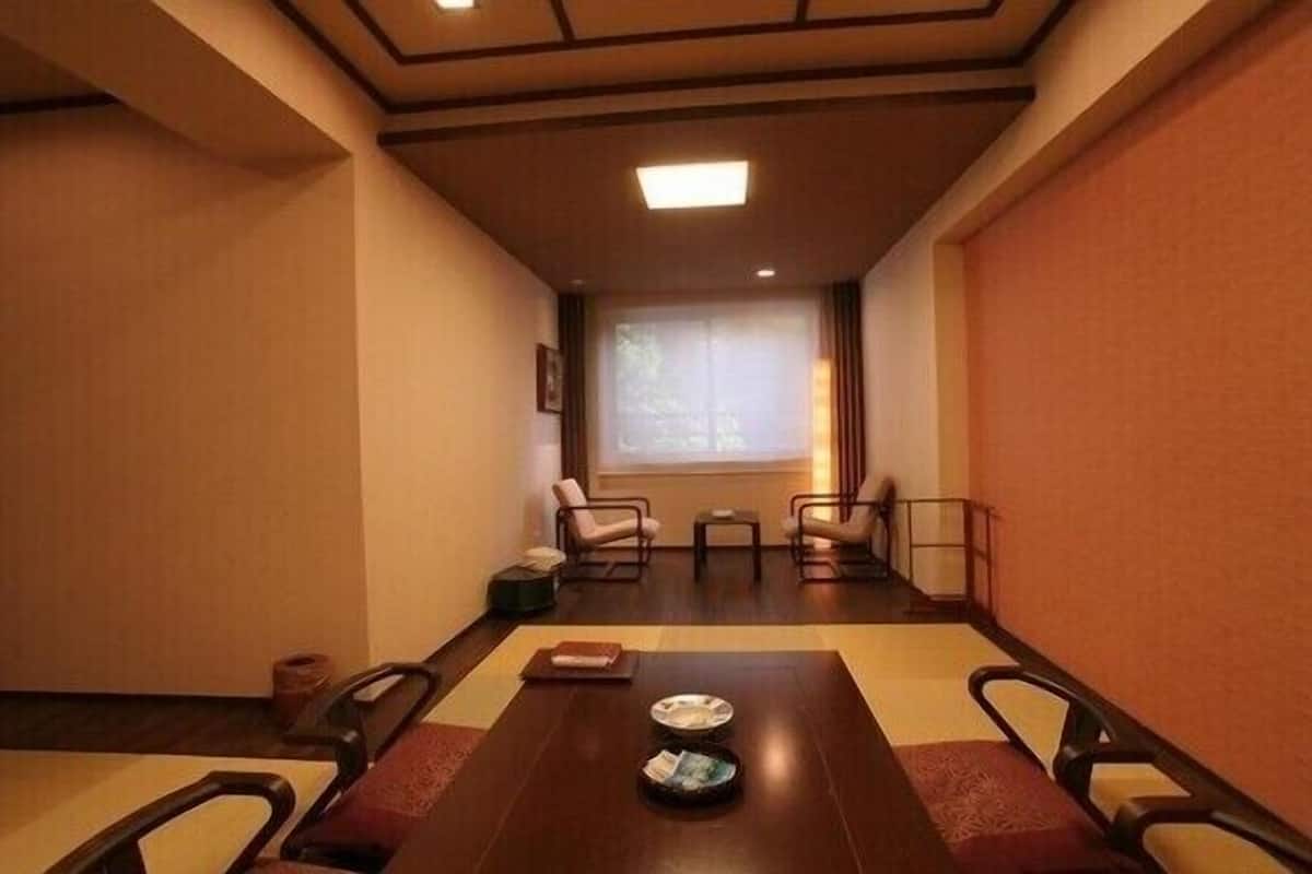 A meeting room with a long table, chairs, a window, and a view of trees outside.