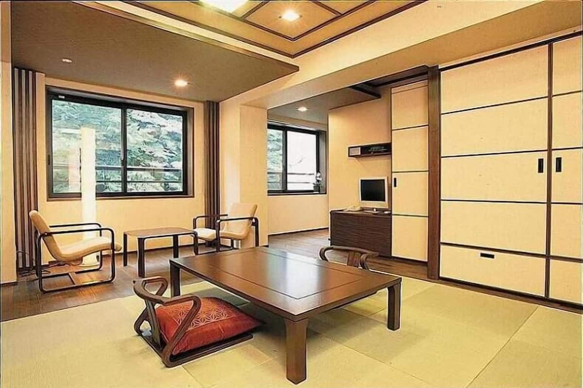 A modern room with a large wooden table, two chairs, a television, and sliding doors.
