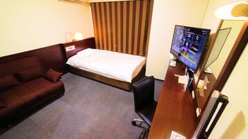 A hotel room with a bed, a sofa, a desk with a computer, and a TV.