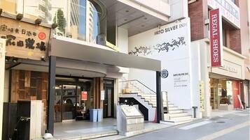 Un bâtiment moderne avec une enseigne bien visible indiquant « Mito Silver Inn » et une entrée clairement identifiable, avec des marches menant à la porte.
