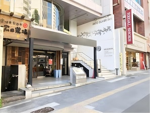 A modern building with a prominent sign for 'Mito Silver Inn' and a visible entrance with steps leading up to the door. - Hotel Mito Silver Inn (Mito)