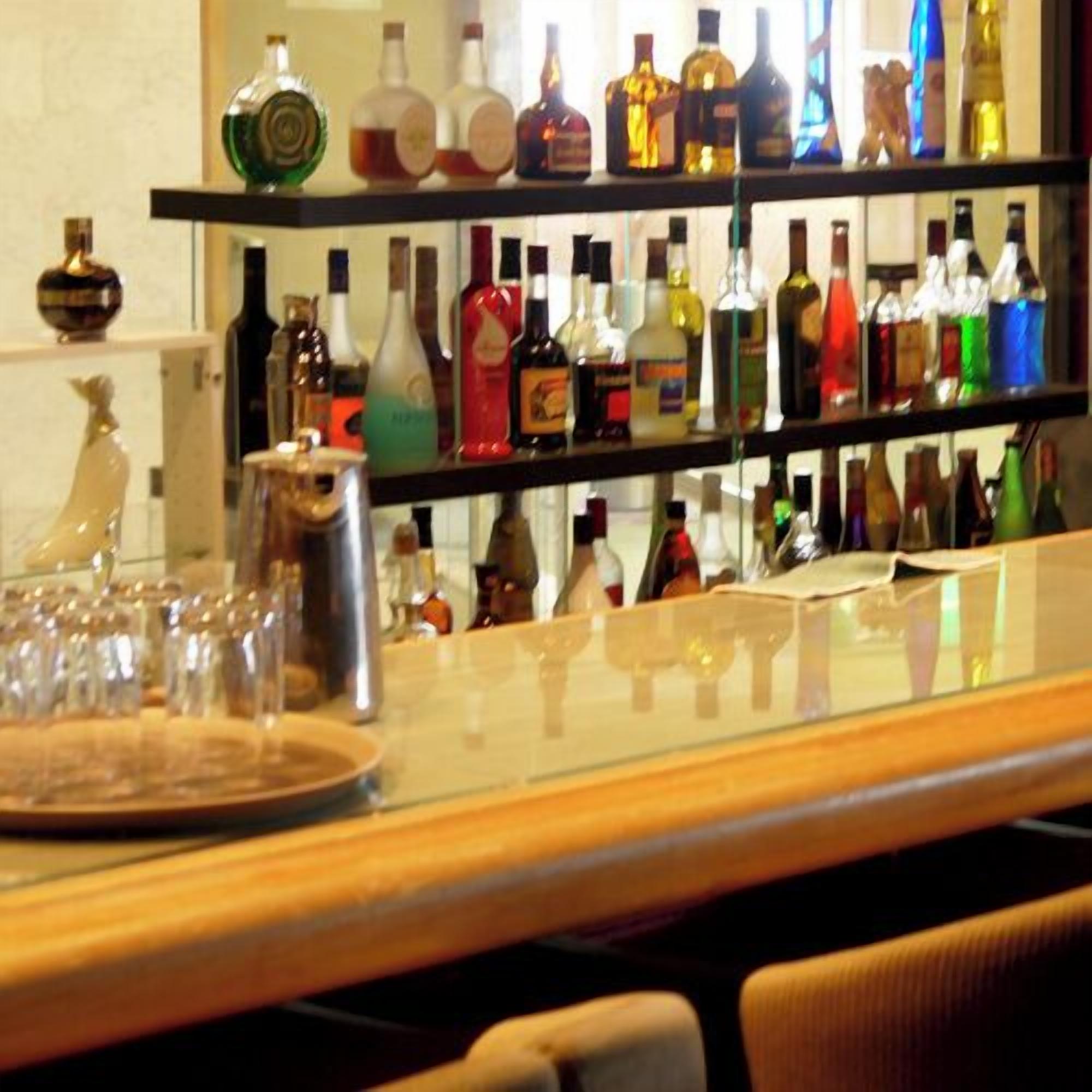 Un espace bar avec des étagères remplies de différentes bouteilles d’alcool et de verres.