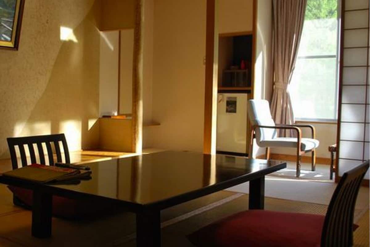 Un comedor con una mesa, sillas, un refrigerador y una ventana con cortinas.