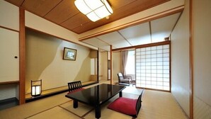 Una habitación japonesa tradicional con suelo de tatami, una mesa baja y puertas correderas.
