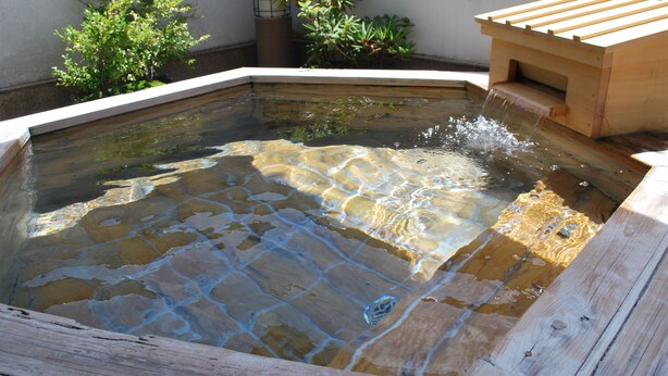 Une source thermale dotée d’une terrasse en bois et d’une petite construction en bois.