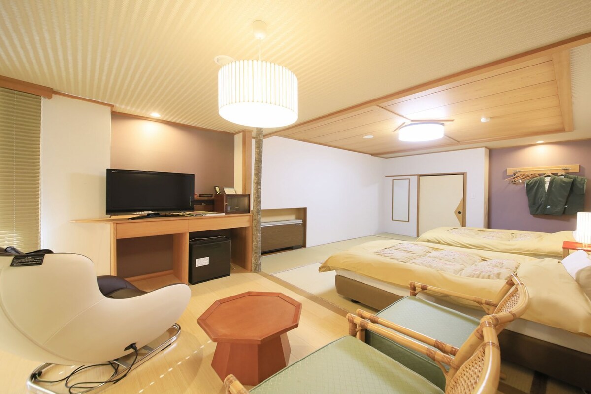 Una habitación de hotel con cama, escritorio, silla y televisor.
