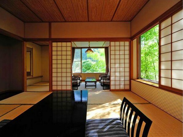 A traditional Japanese room with tatami flooring, sliding doors, and a view of greenery outside. - Ryokan Tanigawa (Minakami)