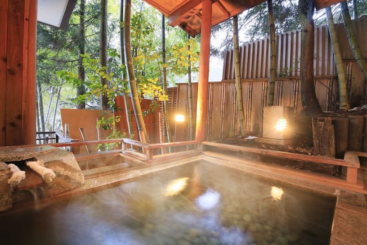 Zona de baños termales con estructuras de madera y bambú.