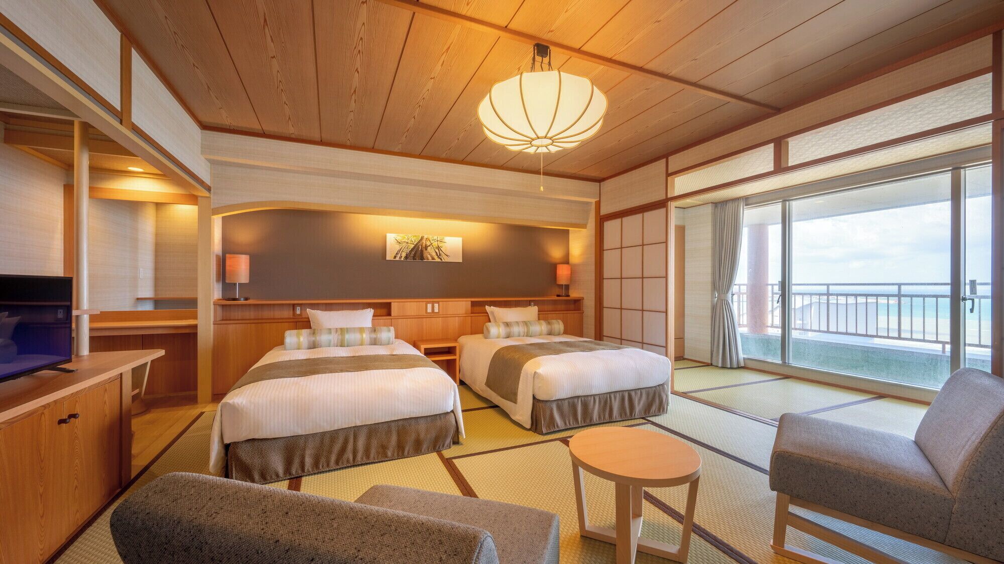A hotel room with two beds, a TV, a small table, and a sofa.