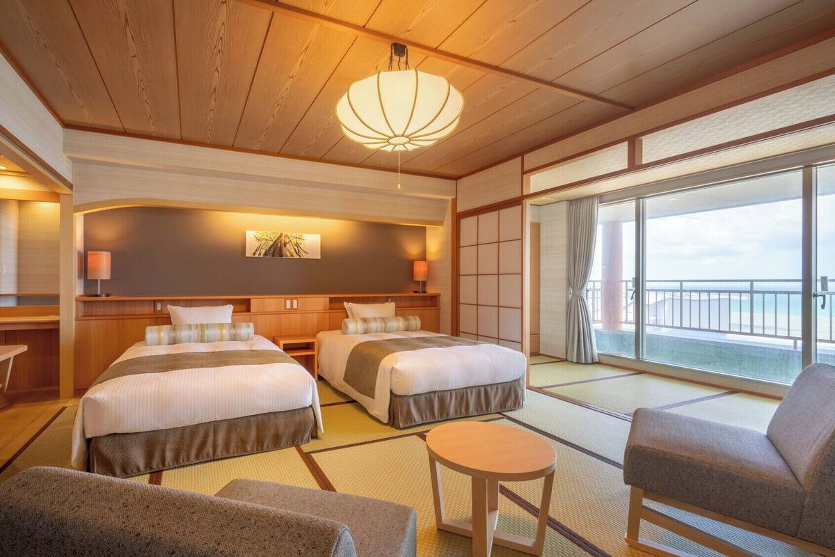 A hotel room with two beds, a TV, a small table, and a sofa.