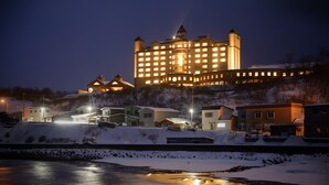 A large, illuminated hotel with multiple towers and a waterfront view. - Hotel Grand Mer Sankaiso (Ajigasawa)