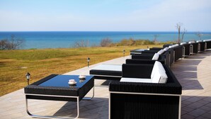 A patio with outdoor seating and a view of the ocean. - Hotel Grand Mer Sankaiso (Ajigasawa)