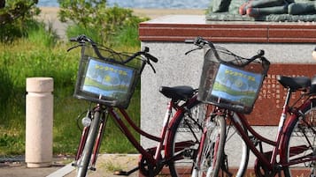 Two bicycles parked next to a stone monument with inscriptions and a statue in the background.