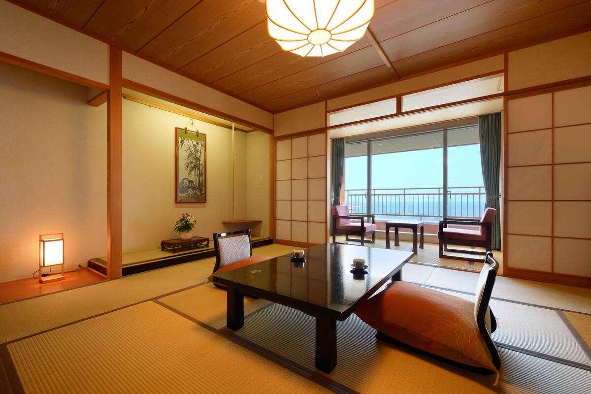 A traditional Japanese room with tatami flooring, a low table, cushions, and sliding doors.