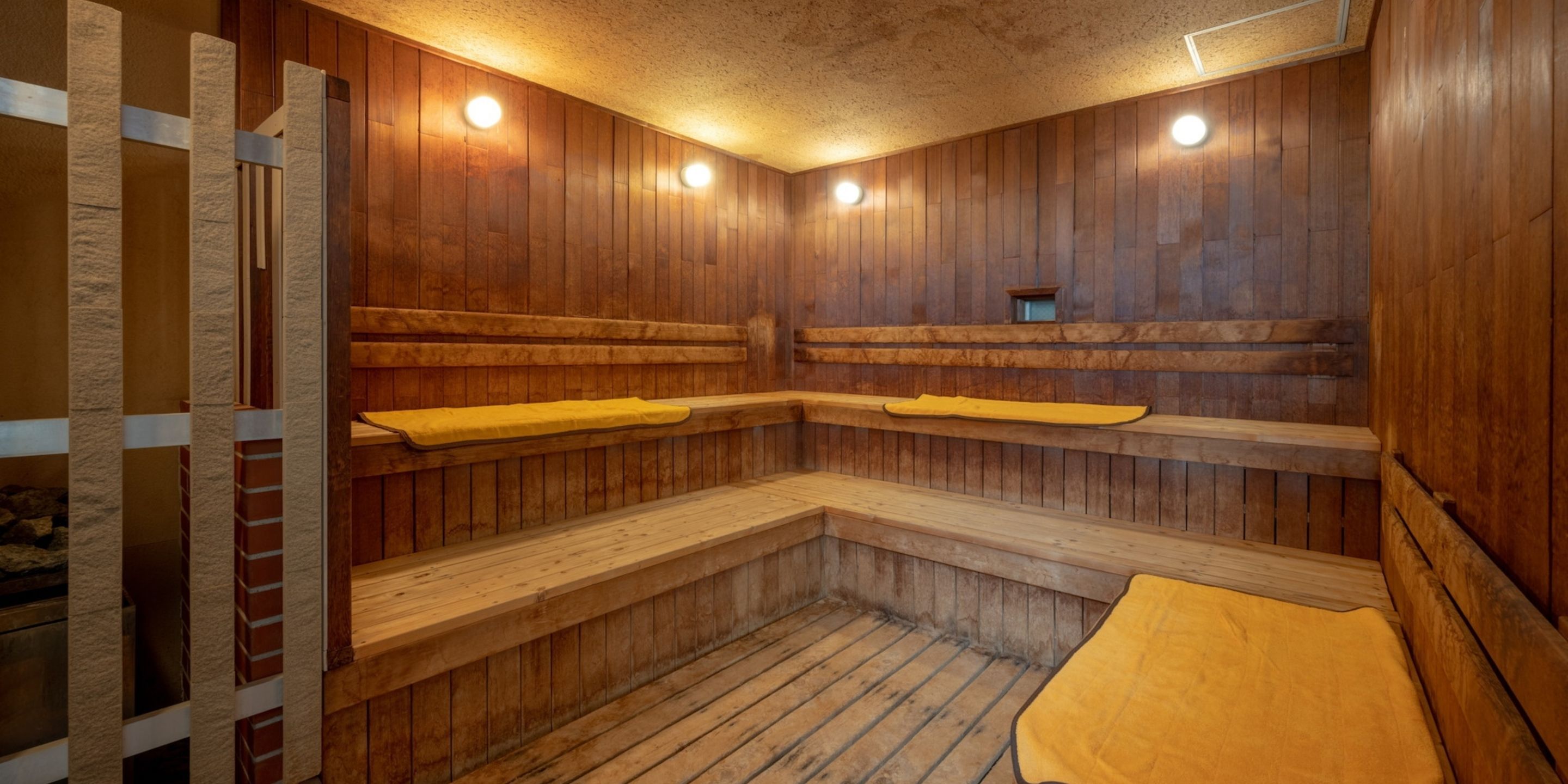 Een sauna met houten banken, een houten vloer en plafondverlichting.