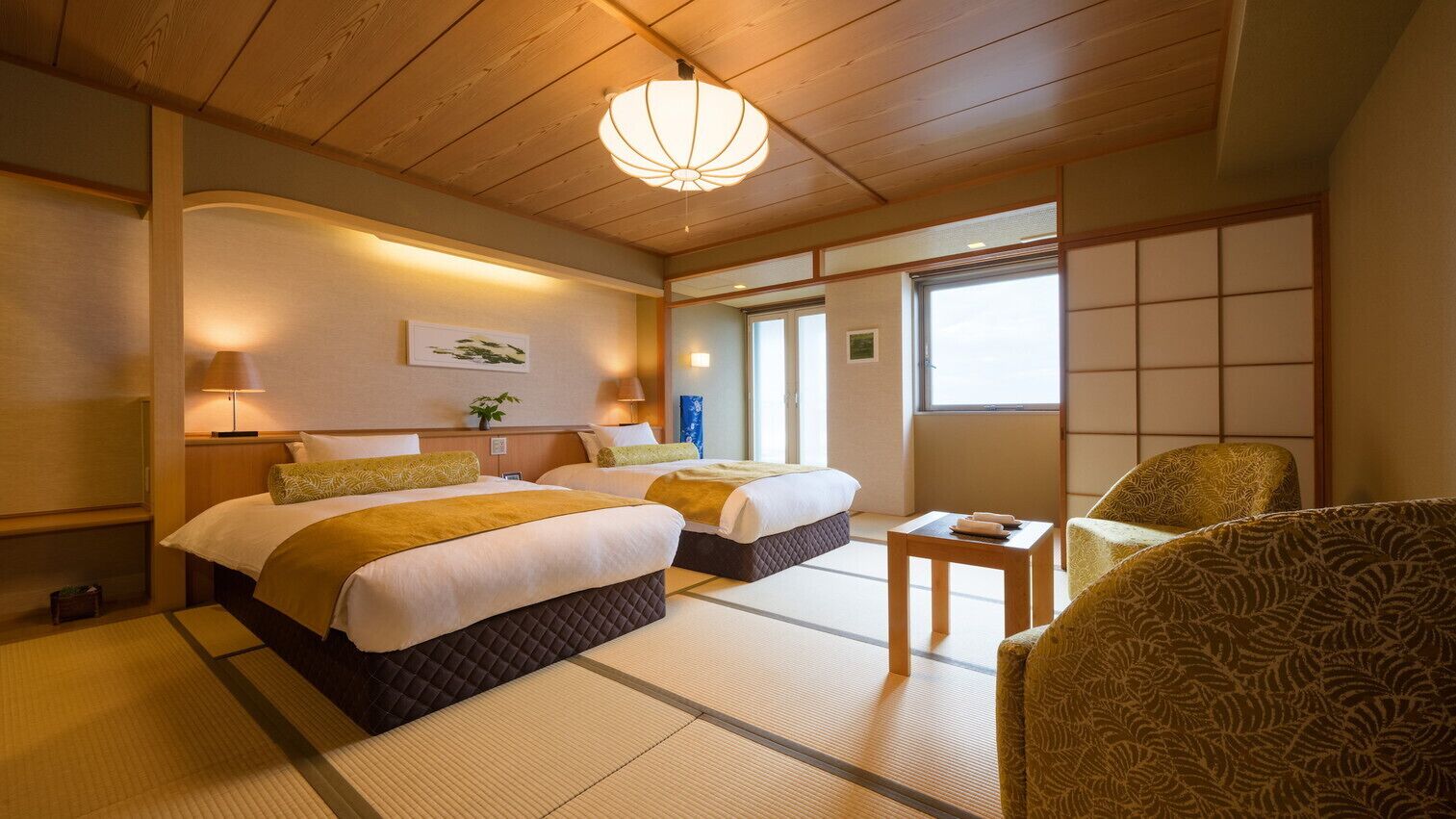 A traditional Japanese-style hotel room with tatami flooring, two beds, a wooden ceiling, and a view of the outside.