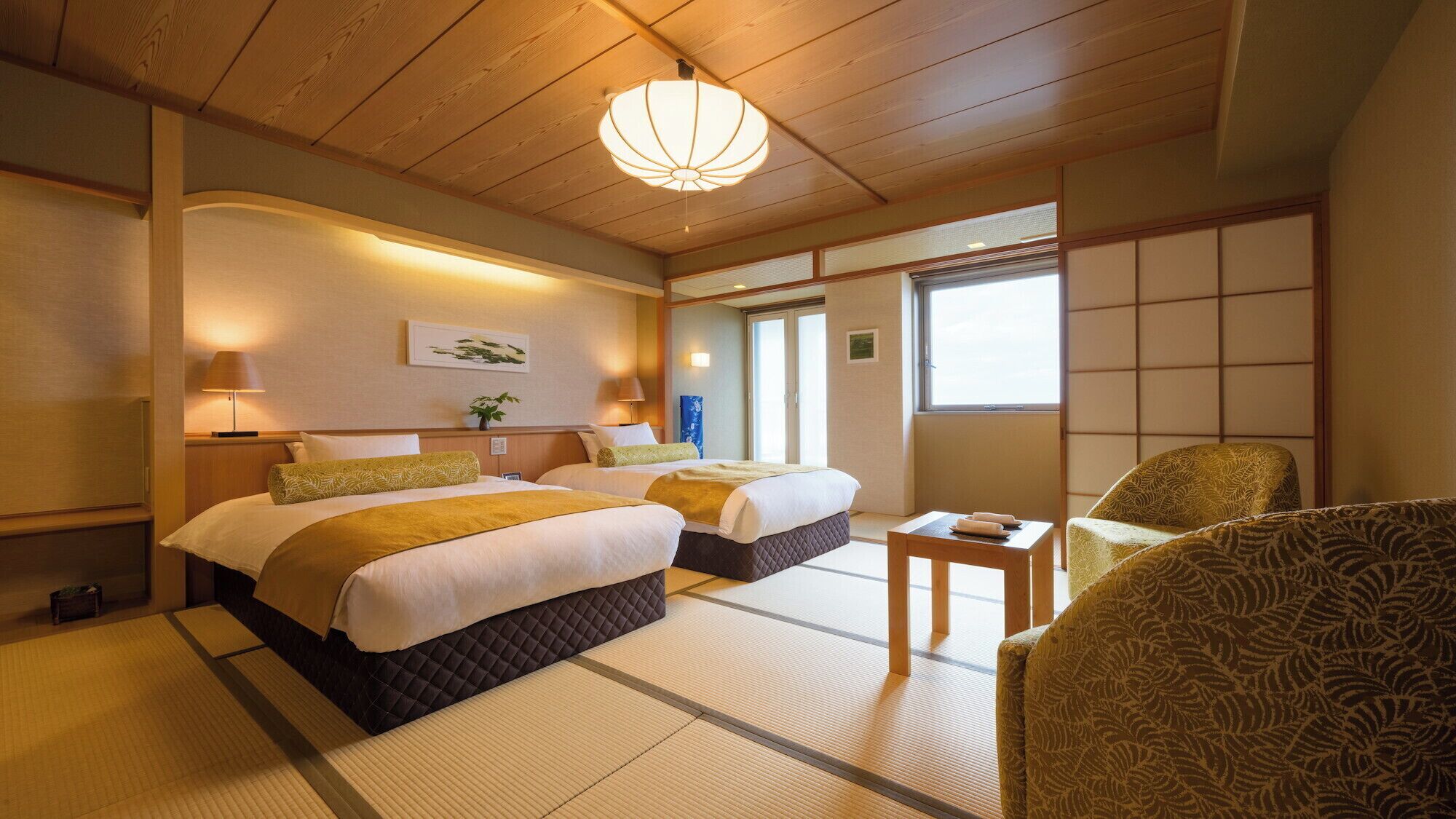 A traditional Japanese-style hotel room with tatami flooring, two beds, a futon, a shoji screen, and a low wooden ceiling.