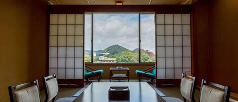 A room with a large window, a wooden table, and four chairs.