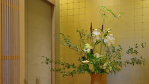 A room with a wooden floor, a large vase with flowers, and a sliding door. - New Hakkeien (Izunokuni)
