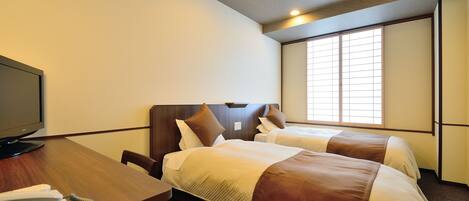 A hotel room with two beds, a desk with a telephone, and a television.