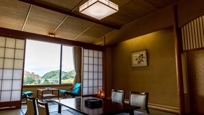 A traditional Japanese room with tatami flooring, a low table, and sliding shoji doors. - New Hakkeien (Izunokuni)
