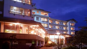 A multi-story hotel with large windows and a covered entrance. - New Hakkeien (Izunokuni)