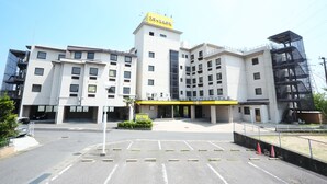 A modern hotel with a central entrance, multiple floors, and a prominent yellow sign.