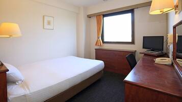 A hotel room with a bed, desk, chair, television, and a window with curtains.