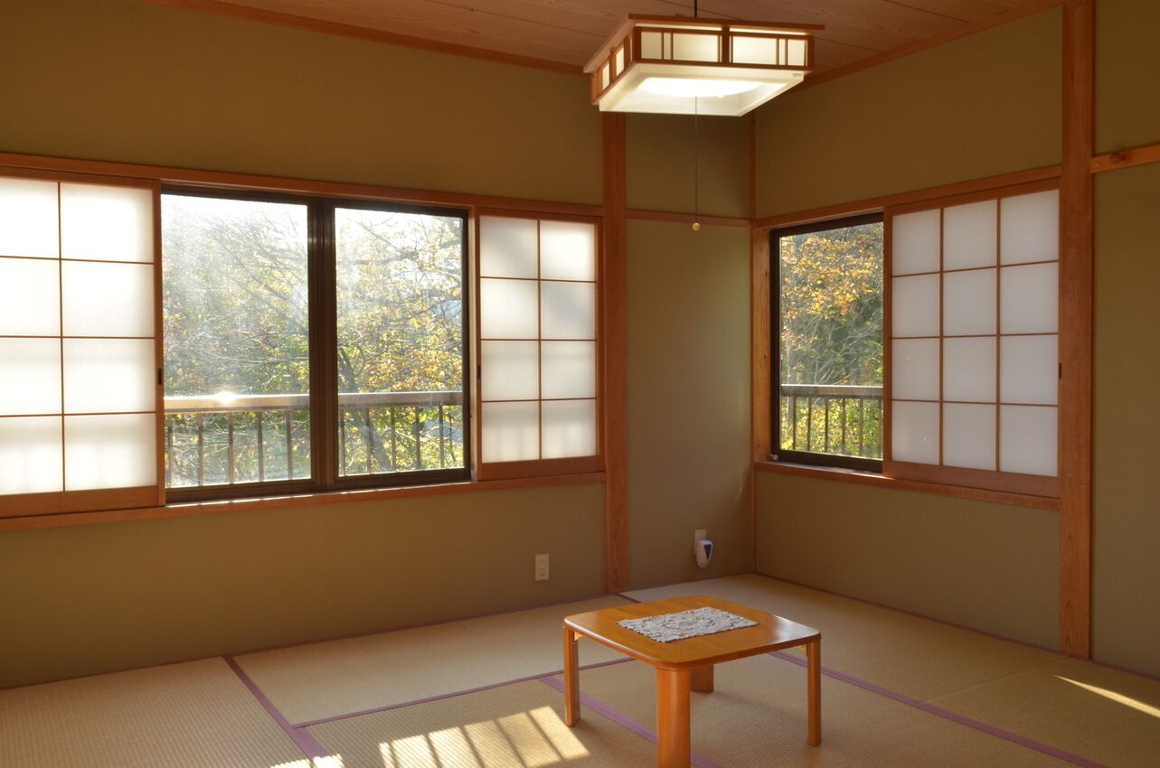 Una habitación tradicional japonesa con suelo de tatami, puertas correderas shoji y una pequeña mesa de madera.