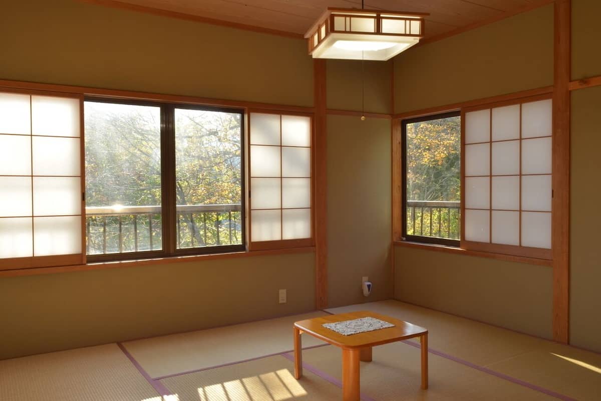 A traditional Japanese room with tatami flooring, sliding shoji doors, and a small wooden table.
