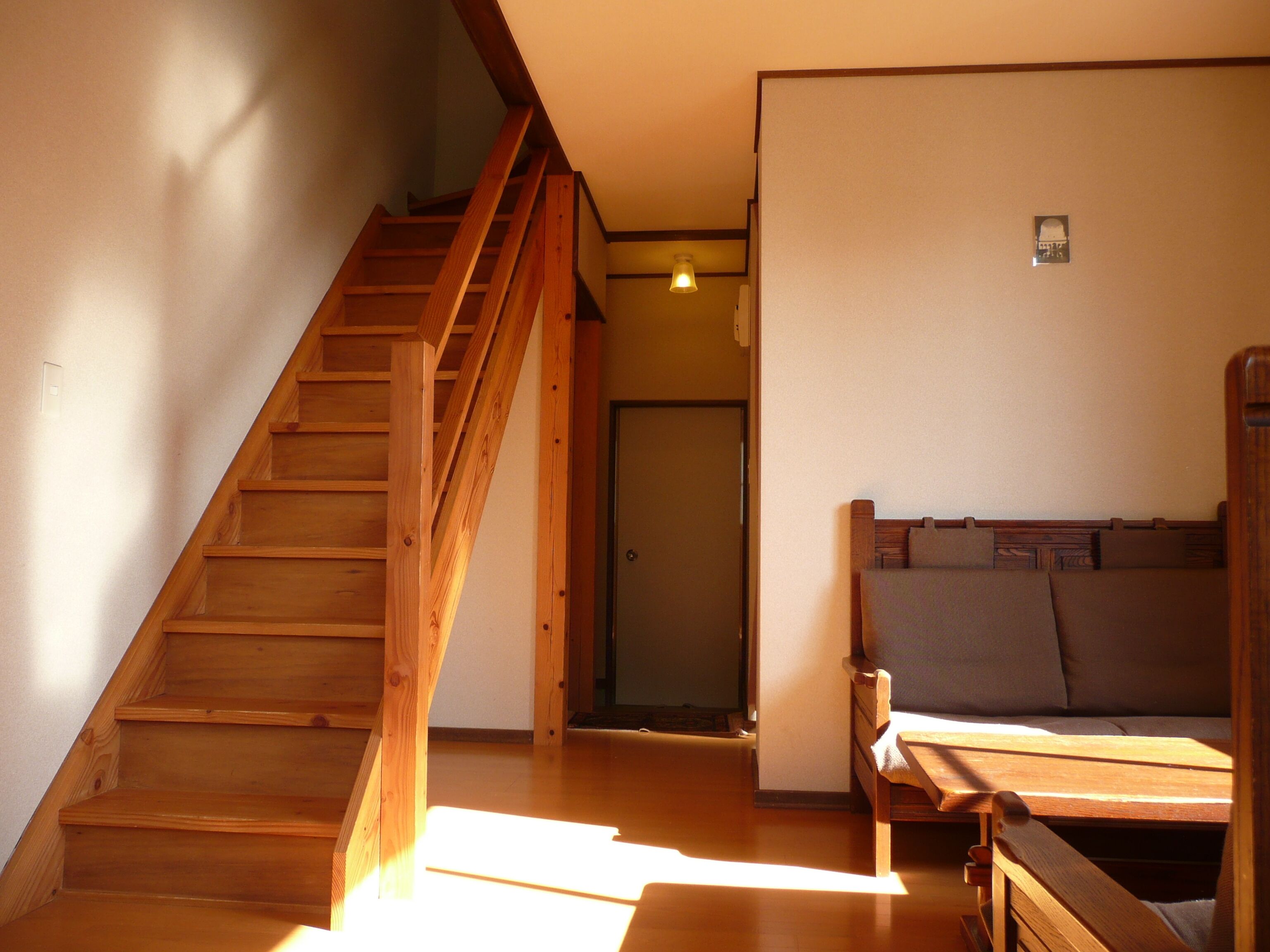 A wooden staircase leading to a room with a bed and a door.