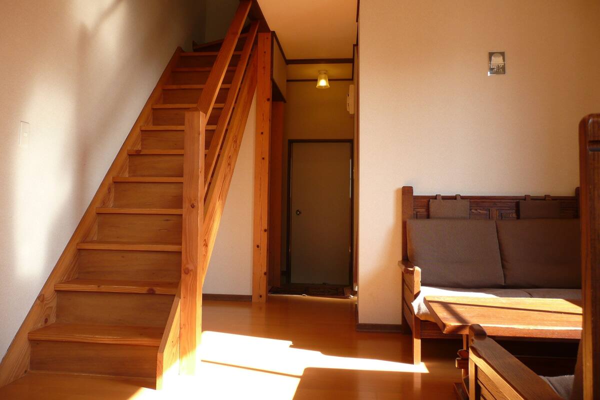 A wooden staircase leading to a room with a bed and a door.