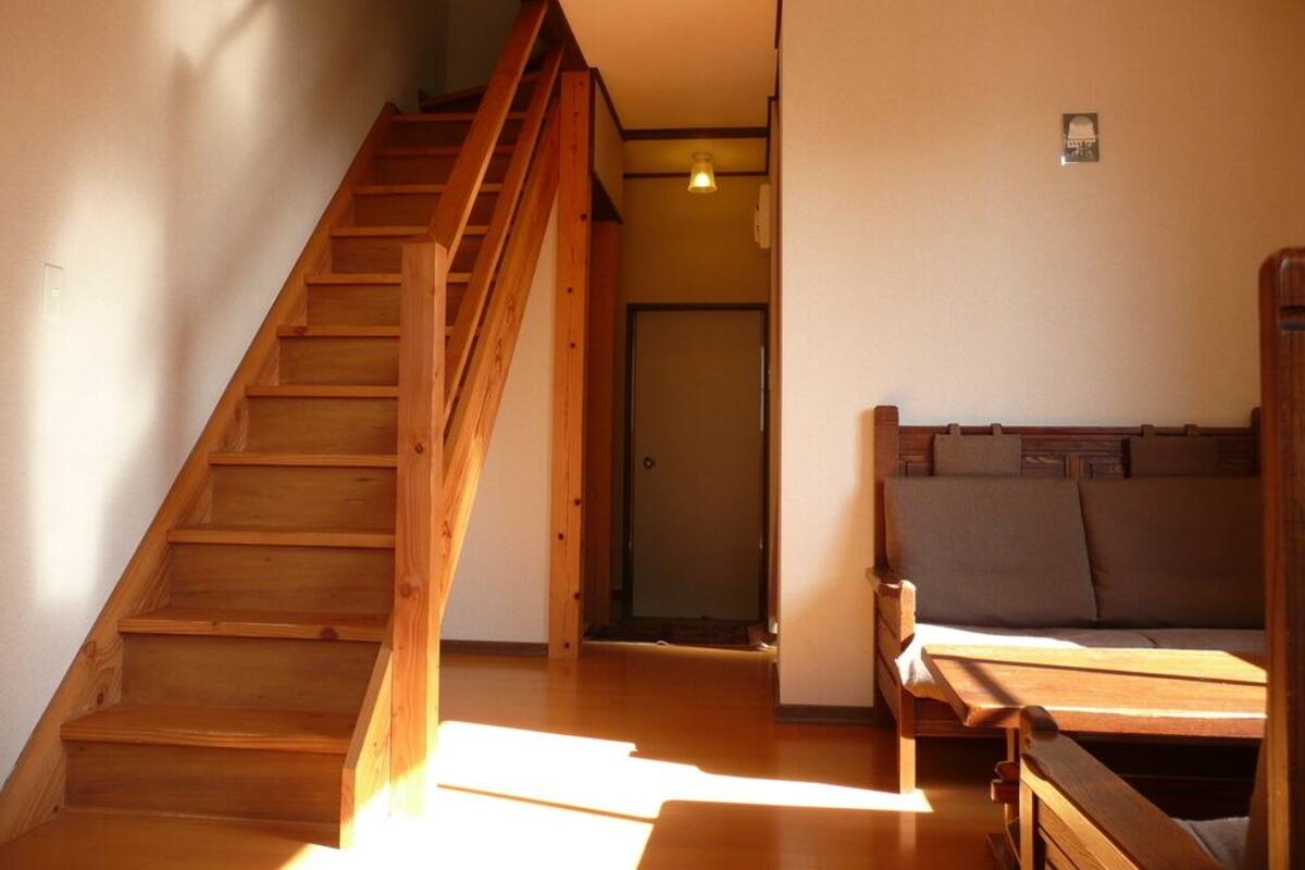 A wooden staircase leading to a room with a bed and a door.
