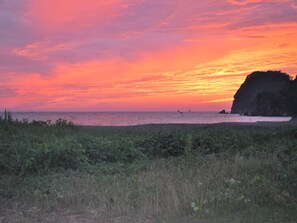 Un paisaje costero con una roca destacada y un atardecer sobre el océano.