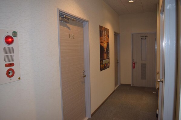 A hallway with doors numbered 102 and 103, a fire alarm, and a poster on the wall.
