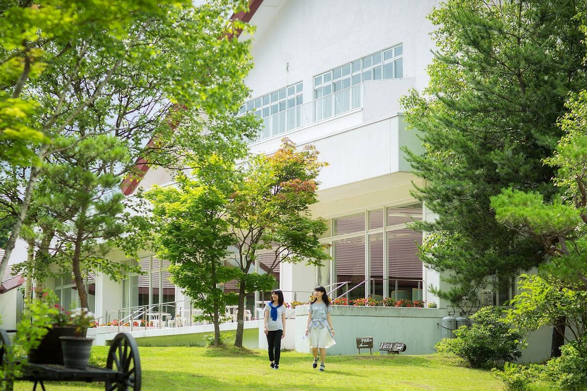 A building with large windows, a grassy courtyard, and a few trees.