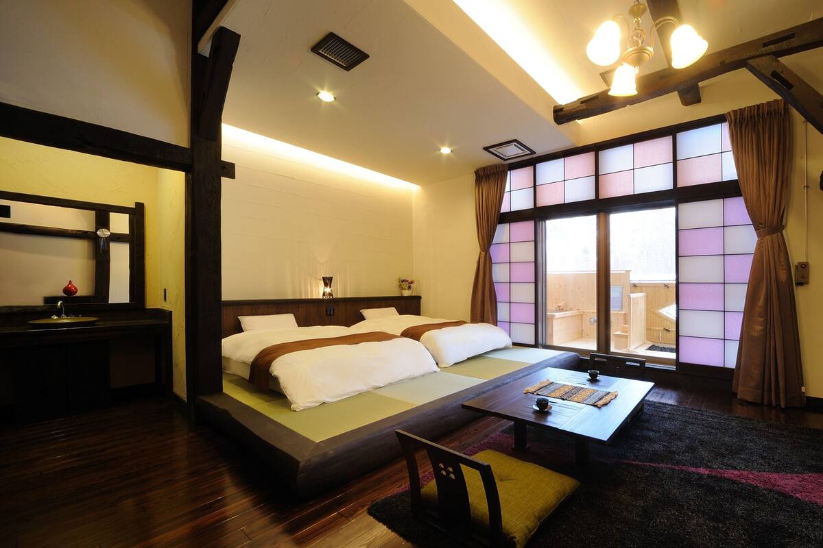 A hotel room with a bed, a desk, a TV, and a window with curtains.